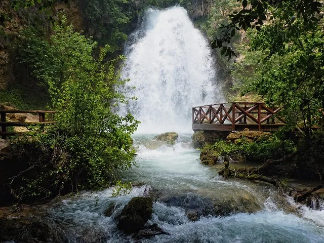 Cascada potente que cae a un arroyo junto a una plataforma de madera