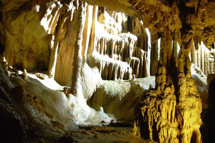 Sonnenlicht erhellt Stalaktiten und Stalagmiten in einer tiefen Höhle