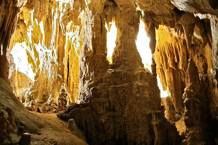 Stalaktiten und Höhlenformationen leuchten im Licht eines Höhleneingangs