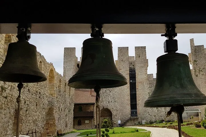 Three church bells hanging before the stone walls of Manasija Monastery